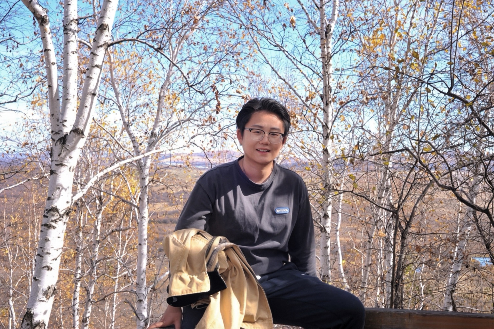 Lee seated among white birch trees in autumn