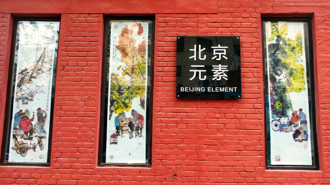 Art displayed in the windows of a red-brick building at Beijing 798 Art Zone